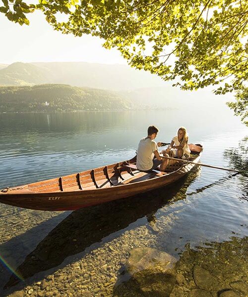 Ein Paar befährt den romantischen Millsättersee mit einem hölzernen Ruderboot