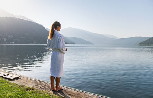 Woman standing on the shore in bathrobe of the Lake Millstätter See