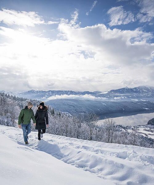 Zwei Menschen gehen Hand in Hand im Schnee spazieren