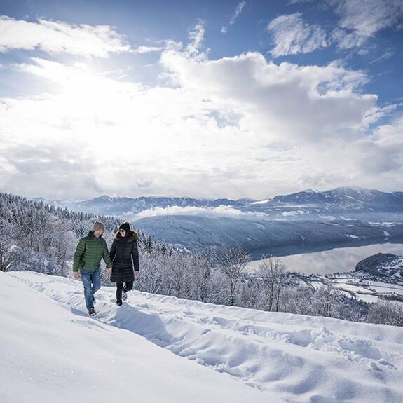 Zwei Menschen gehen Hand in Hand im Schnee spazieren