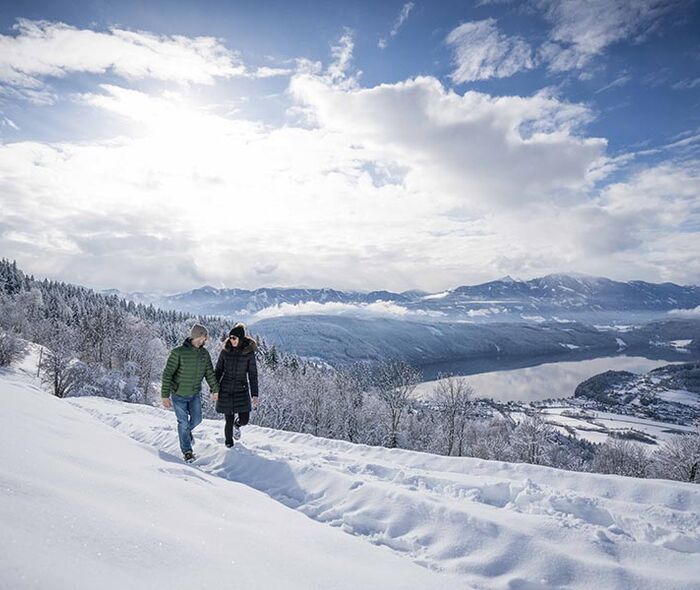 Zwei Menschen gehen Hand in Hand im Schnee spazieren