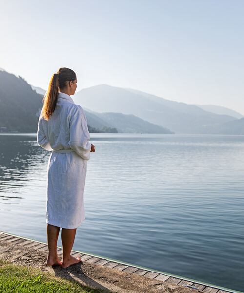 Woman standing on the shore in bathrobe of the Lake Millstätter See